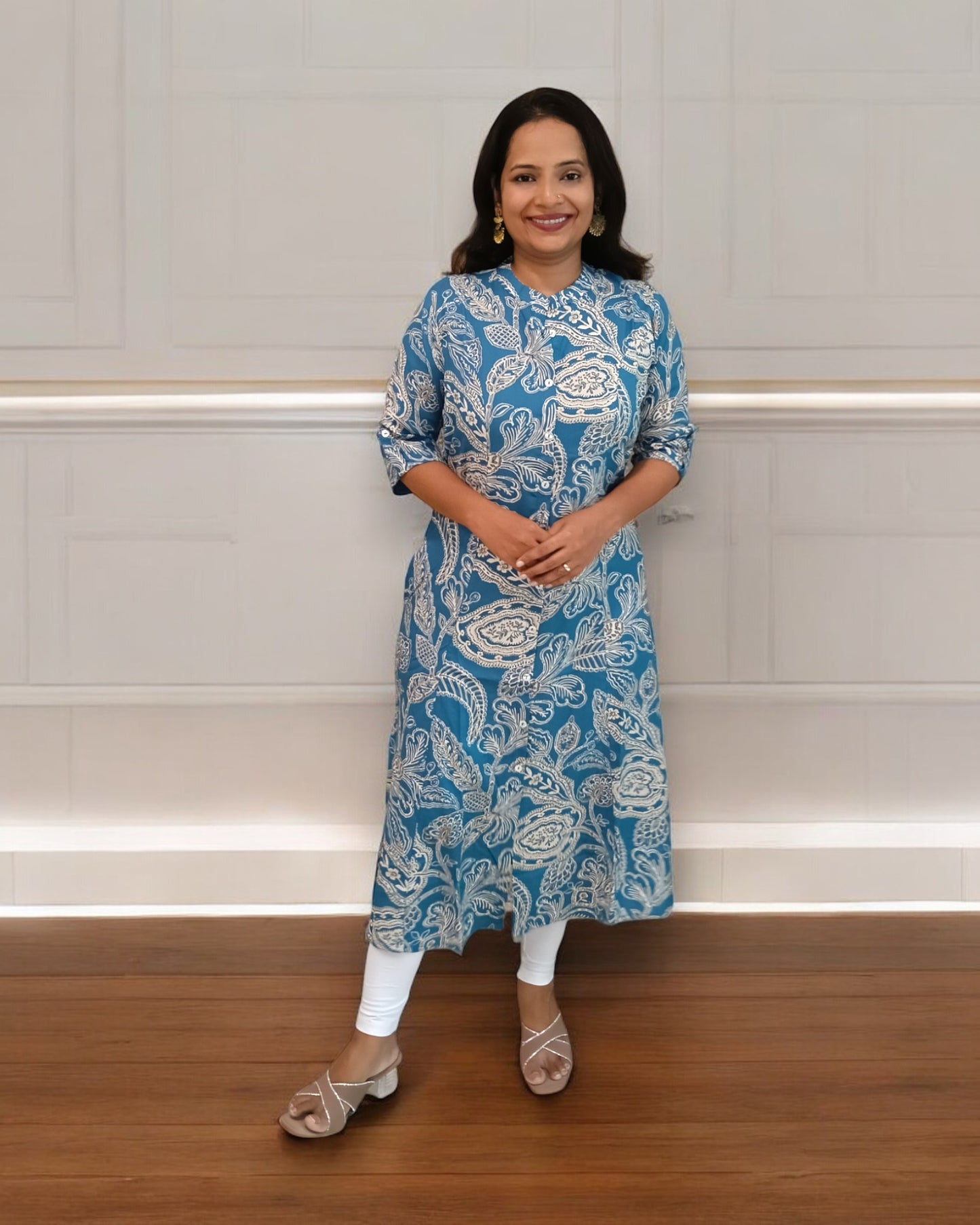 Woman wearing a blue and white patterned kurta standing against a plain background