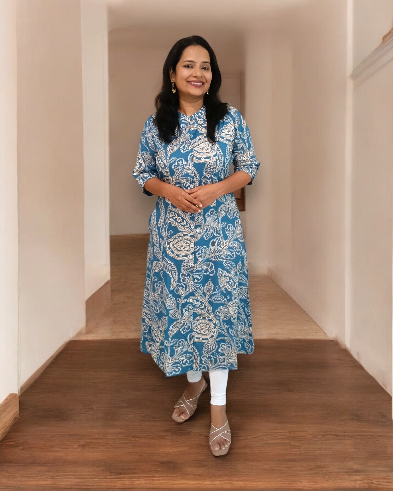 Woman wearing a blue patterned kurta standing on a wooden floor.