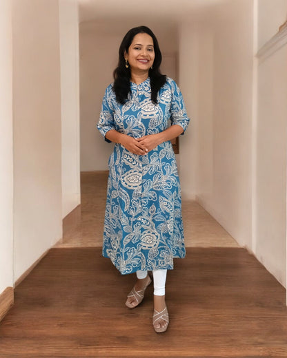 Woman wearing a blue patterned kurta standing on a wooden floor.