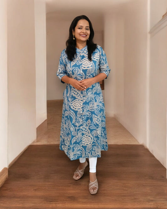Woman wearing a blue patterned kurta standing on a wooden floor.